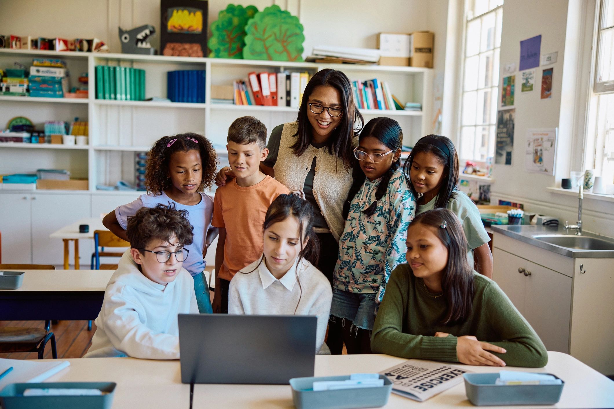 Instructor guiding learners around a laptop during a workshop